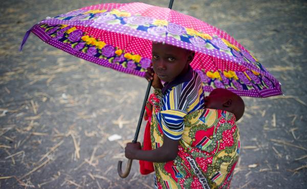 A child holds an umbrella as refugees at a refugee camp in Palorinya, Uganda. A child holds an umbrella as refugees at a refugee camp in Palorinya, Uganda.