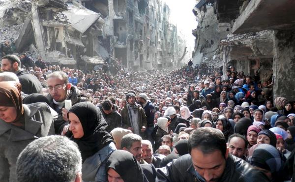 A photo taken in January 2014 and released by the United Nations Relief and Works Agency for Palestine Refugees (UNRWA), shows residents of the besieged Palestinian camp of Yarmouk, queuing to receive food supplies, in Damascus, Syria. A photo taken in January 2014 and released by the United Nations Relief and Works Agency for Palestine Refugees (UNRWA), shows residents of the besieged Palestinian camp of Yarmouk, queuing to receive food supplies, in Damascus, Syria.