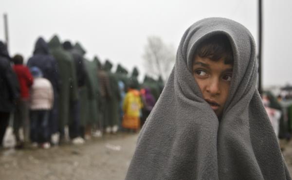 A migrant child covered by a blanket stands in the rain at the northern Greek border station at Idomeni on Thursday. A migrant child covered by a blanket stands in the rain at the northern Greek border station at Idomeni on Thursday.