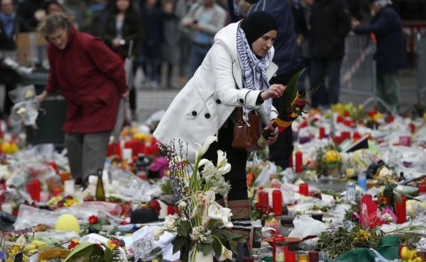 A woman helps readjust the tributes in the Place de la Bourse, left for the victims of the recent bomb attacks in Brussels. A woman helps readjust the tributes in the Place de la Bourse, left for the victims of the recent bomb attacks in Brussels.