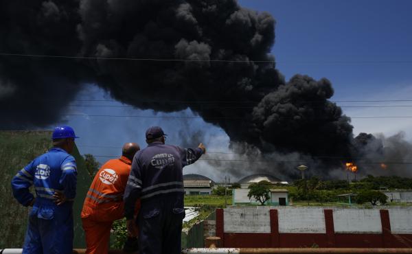 Workers of the Cuba Oil Union, known by the Spanish acronym CUPET, watch a huge rising plume of smoke from the Matanzas Supertanker Base, as firefighters work to quell a blaze which began during a thunderstorm the night before, in Matazanas, Cuba, Saturda Workers of the Cuba Oil Union, known by the Spanish acronym CUPET, watch a huge rising plume of smoke from the Matanzas Supertanker Base, as firefighters work to quell a blaze which began during a thunderstorm the night before, in Matazanas, Cuba, Saturda