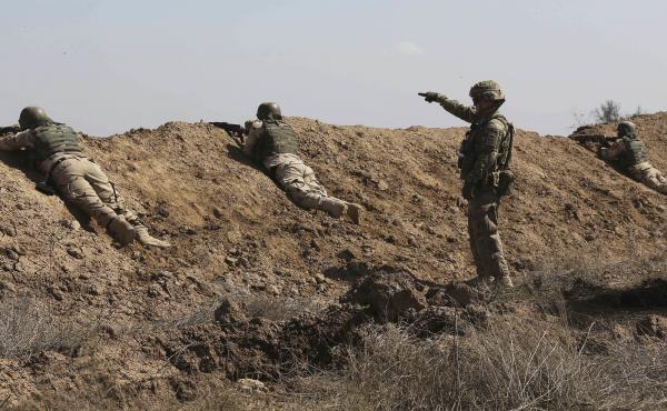 A U.S. soldier (standing) helps Iraqi security forces improve shooting skills at Camp Taji, north of Baghdad, in 2015. A U.S. soldier (standing) helps Iraqi security forces improve shooting skills at Camp Taji, north of Baghdad, in 2015.