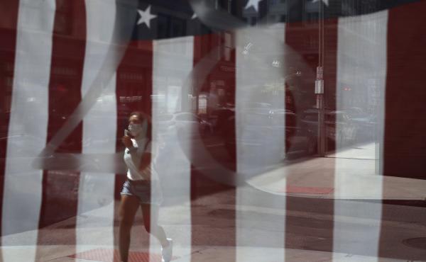 A passerby wears a mask out of concern for the coronavirus while walking past an American flag displayed in Boston on Tuesday. The U.S. has now recorded more than 3 million confirmed cases of the coronavirus. A passerby wears a mask out of concern for the coronavirus while walking past an American flag displayed in Boston on Tuesday. The U.S. has now recorded more than 3 million confirmed cases of the coronavirus.