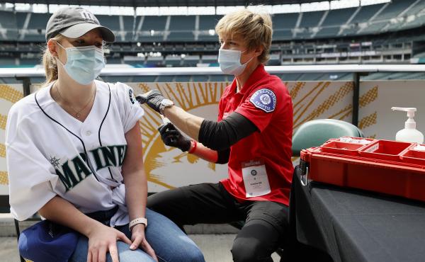 Sydney Porter of Bellevue, Wash., receives her COVID-19 vaccination from Kristine Gill, with the Seattle Fire Department's Mobile Vaccination Teams, before the game between the Seattle Mariners and the Baltimore Orioles at T-Mobile Park on May 5 in Seattl Sydney Porter of Bellevue, Wash., receives her COVID-19 vaccination from Kristine Gill, with the Seattle Fire Department's Mobile Vaccination Teams, before the game between the Seattle Mariners and the Baltimore Orioles at T-Mobile Park on May 5 in Seattl