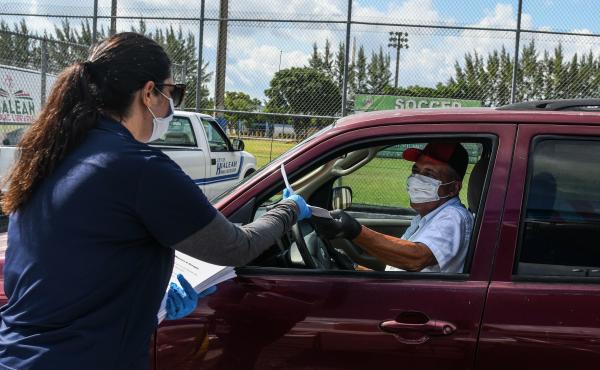 A man collects unemployment forms at a drive-through collection point outside of a library in Hialeah, Fla., on Wednesday. A man collects unemployment forms at a drive-through collection point outside of a library in Hialeah, Fla., on Wednesday.