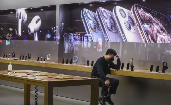 An employee wears a protective mask as he sits in the showroom of an Apple Store after it closed Saturday in Beijing. Apple announced it was closing all 42 of its stores in China until February 10 due to the coronavirus outbreak. An employee wears a protective mask as he sits in the showroom of an Apple Store after it closed Saturday in Beijing. Apple announced it was closing all 42 of its stores in China until February 10 due to the coronavirus outbreak.