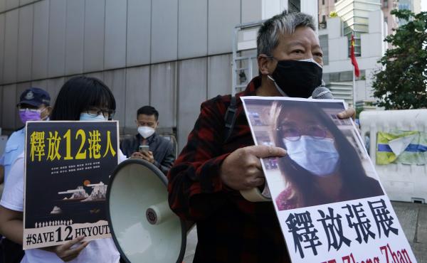 Pro-democracy activists (right) hold placards with the picture of Chinese citizen journalist Zhang Zhan as they march to the Chinese central government's liaison office in Hong Kong in Dec. 2020. Pro-democracy activists (right) hold placards with the picture of Chinese citizen journalist Zhang Zhan as they march to the Chinese central government's liaison office in Hong Kong in Dec. 2020.