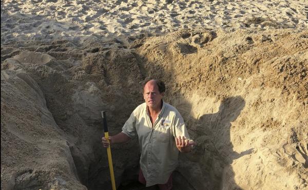 David Elder, ocean rescue supervisor for Kill Devil Hills, N.C, stands in a hole he estimates to be 7 feet deep on Sunday. The town on North Carolina's Outer Banks has issued a plea to beachgoers about the dangers of digging holes on the beach. David Elder, ocean rescue supervisor for Kill Devil Hills, N.C, stands in a hole he estimates to be 7 feet deep on Sunday. The town on North Carolina's Outer Banks has issued a plea to beachgoers about the dangers of digging holes on the beach.