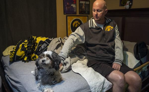Jon Miller sits in his bedroom with his dog, Carlos, whom he received as a present for successfully completing cancer treatment a decade ago. Miller sustained severe brain damage, and requires the help of home health aides to continue living in his home. Jon Miller sits in his bedroom with his dog, Carlos, whom he received as a present for successfully completing cancer treatment a decade ago. Miller sustained severe brain damage, and requires the help of home health aides to continue living in his home.