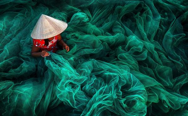 In a village in southern Vietnam, a woman weaves a fishing net. By tradition, Vietnamese women make nets for their husbands. In a village in southern Vietnam, a woman weaves a fishing net. By tradition, Vietnamese women make nets for their husbands.