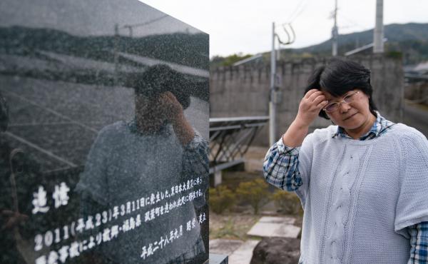 Chiyomi Endo stands beside her husband's grave. "Remember that this family evacuated Futaba town, Fukushima prefecture," the stone reads, "and moved here due to the nuclear accident following the Great East Japan Earthquake that occurred on March 11, 2011 Chiyomi Endo stands beside her husband's grave. "Remember that this family evacuated Futaba town, Fukushima prefecture," the stone reads, "and moved here due to the nuclear accident following the Great East Japan Earthquake that occurred on March 11, 2011