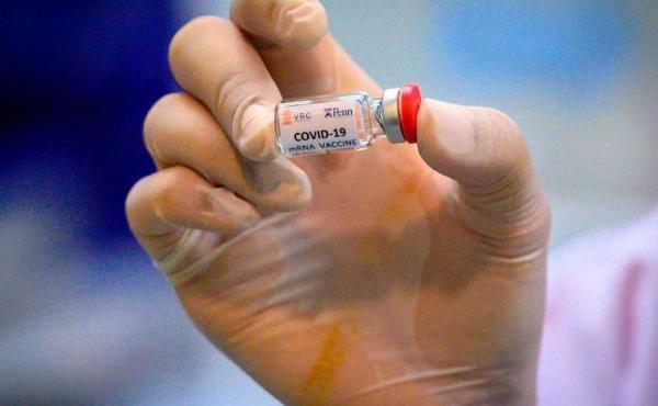 A laboratory technician holds a dose of a COVID-19 vaccine candidate ready for a trial in May 2020. A laboratory technician holds a dose of a COVID-19 vaccine candidate ready for a trial in May 2020.
