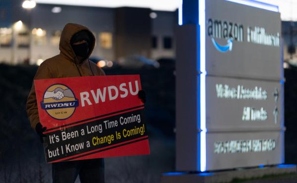 A retail union representative holds a sign by the Amazon warehouse in Bessemer, Ala., during the first union election in March 2021. A retail union representative holds a sign by the Amazon warehouse in Bessemer, Ala., during the first union election in March 2021.