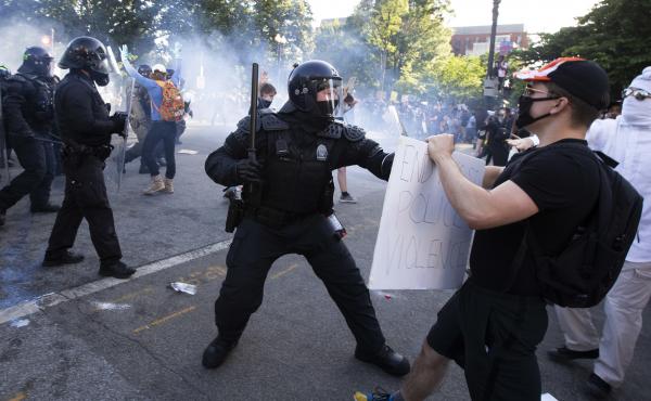 A law enforcement officer raises a baton and tear gas is fired during protests near the White House on June 1. A law enforcement officer raises a baton and tear gas is fired during protests near the White House on June 1.