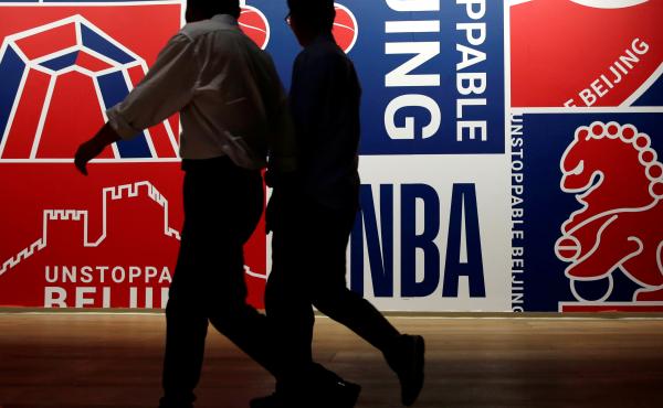 Men walk past a poster at an NBA exhibition in Beijing on Oct. 8. Men walk past a poster at an NBA exhibition in Beijing on Oct. 8.