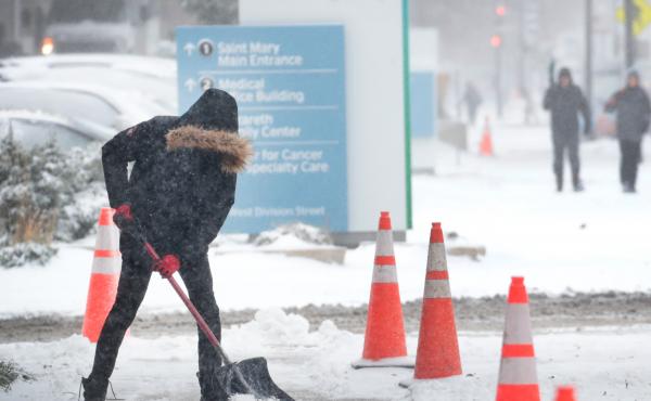 A worker shovels snow from a sidewalk in the Humboldt Park neighborhood of Chicago. Forecasters expect temperatures to drop around 10 degrees by Wednesday. A worker shovels snow from a sidewalk in the Humboldt Park neighborhood of Chicago. Forecasters expect temperatures to drop around 10 degrees by Wednesday.