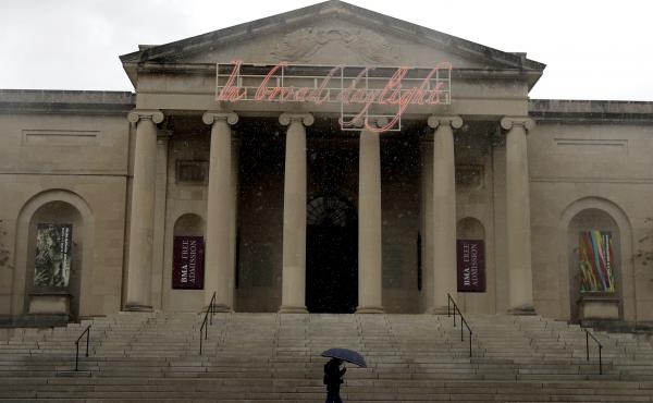 A man covers himself from rain with an umbrella as he walks by the Baltimore Museum of Art on April 21, 2020. An upcoming exhibit at the museum will be curated by security guards. A man covers himself from rain with an umbrella as he walks by the Baltimore Museum of Art on April 21, 2020. An upcoming exhibit at the museum will be curated by security guards.