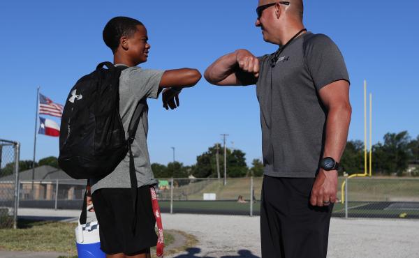 Football coach Bob Wager (right) and sophomore safety Cameron Conley greet each other Thursday at the reopening of strength and conditioning camp at Martin High School in Arlington, Texas. State officials say they plan to open schools for in-person instru Football coach Bob Wager (right) and sophomore safety Cameron Conley greet each other Thursday at the reopening of strength and conditioning camp at Martin High School in Arlington, Texas. State officials say they plan to open schools for in-person instru