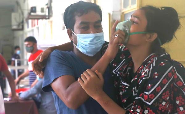A man assists a patient with difficulty breathing at the Medical College Hospital in Rajshahi, Bangladesh, on June 16, as the delta variant of the coronavirus quickly spread. A man assists a patient with difficulty breathing at the Medical College Hospital in Rajshahi, Bangladesh, on June 16, as the delta variant of the coronavirus quickly spread.