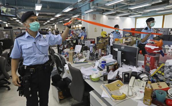 Hong Kong police officers search the newsroom of the Apple Daily newspaper Monday after arresting the paper's publisher, Jimmy Lai. Hong Kong police officers search the newsroom of the Apple Daily newspaper Monday after arresting the paper's publisher, Jimmy Lai.