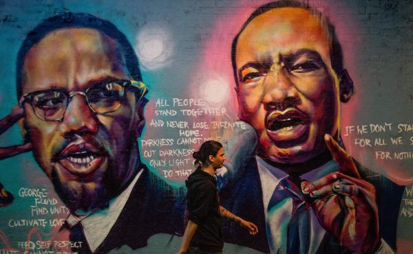 A man walks past a mural of Malcom X and Martin Luther King Jr. in London. A man walks past a mural of Malcom X and Martin Luther King Jr. in London.