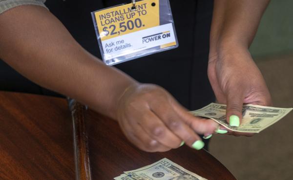 A manager of a financial services store in Ballwin, Mo., counts cash being paid to a client as part of a loan in 2018. Consumer groups blasted a new payday lending rule and its timing during a pandemic that has put tens of millions of people out of work. A manager of a financial services store in Ballwin, Mo., counts cash being paid to a client as part of a loan in 2018. Consumer groups blasted a new payday lending rule and its timing during a pandemic that has put tens of millions of people out of work.