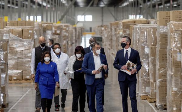 Gov. Gavin Newsom, right, walks through rows of boxed personal protective equipment with dignitaries and elected officials, as he prepares to announce the next phase of California's COVID-19 response on Thursday. Gov. Gavin Newsom, right, walks through rows of boxed personal protective equipment with dignitaries and elected officials, as he prepares to announce the next phase of California's COVID-19 response on Thursday.