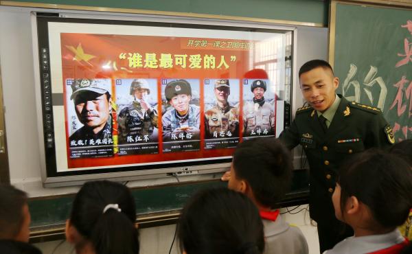 A paramilitary police officer talks next to a screen showing frontier soldiers of the People's Liberation Army during an event at a primary school in Wuzhishan, Hainan province, China, on Feb. 22. On the screen are (L-R) Qi Fabao, who was seriously wounde A paramilitary police officer talks next to a screen showing frontier soldiers of the People's Liberation Army during an event at a primary school in Wuzhishan, Hainan province, China, on Feb. 22. On the screen are (L-R) Qi Fabao, who was seriously wounde