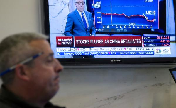 U.S. stocks fell sharply Monday after China retaliated for President Trump's latest round of tariffs. Here, a trader works on the floor at the New York Stock Exchange as a TV shows the state of the market. U.S. stocks fell sharply Monday after China retaliated for President Trump's latest round of tariffs. Here, a trader works on the floor at the New York Stock Exchange as a TV shows the state of the market.
