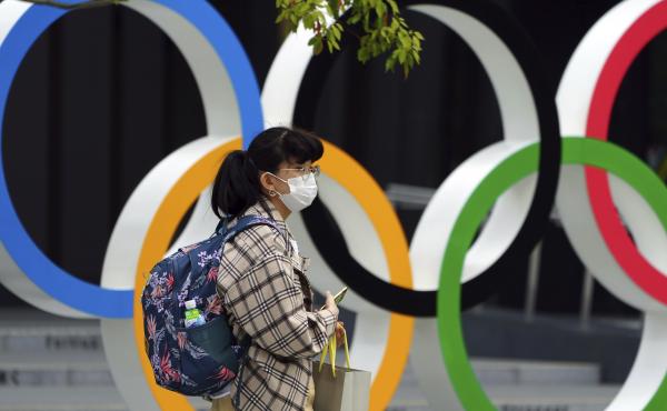 A woman wearing a protective mask to help curb the spread of the coronavirus walks in front of he Olympic Rings on Tuesday in Tokyo. North Korea says it will not attend the games over COVID-19 fears. A woman wearing a protective mask to help curb the spread of the coronavirus walks in front of he Olympic Rings on Tuesday in Tokyo. North Korea says it will not attend the games over COVID-19 fears.