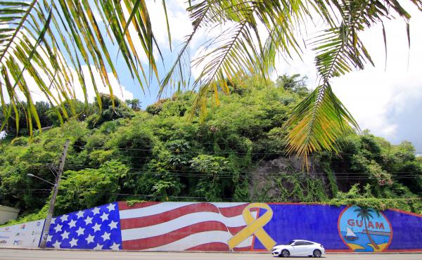 Afternoon traffic passes in front of a mural depicting the U.S. and Guam flags in the Tumon district on the island of Guam. Afternoon traffic passes in front of a mural depicting the U.S. and Guam flags in the Tumon district on the island of Guam.