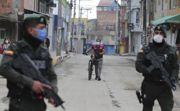 Police stand guard during a government order for residents to stay home, to help contain the spread of the new coronavirus, as a resident walks to a food store in Soacha on the outskirts of Bogotá, Colombia, on March 25. Police stand guard during a government order for residents to stay home, to help contain the spread of the new coronavirus, as a resident walks to a food store in Soacha on the outskirts of Bogotá, Colombia, on March 25.