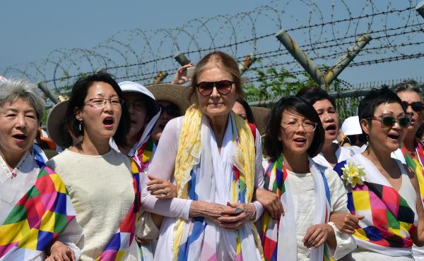 Gloria Steinem and South Korean peace activists march along a military fence at a checkpoint after crossing the border separating North and South Korea. Gloria Steinem and South Korean peace activists march along a military fence at a checkpoint after crossing the border separating North and South Korea.
