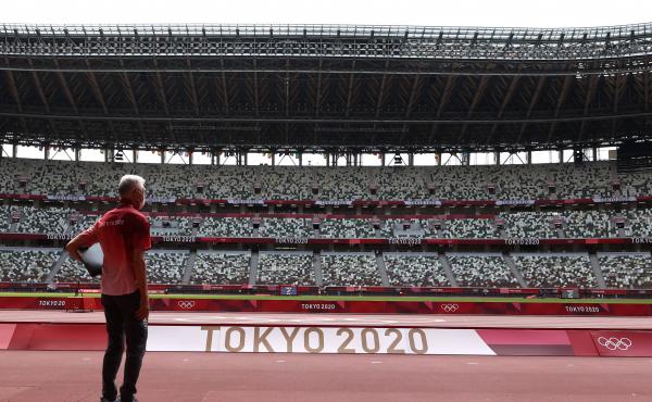 A passerby looks on while wearing a protective face covering inside an empty Olympic Stadium, host to the Athletics competition, at the Tokyo Olympic Games on Thursday. A passerby looks on while wearing a protective face covering inside an empty Olympic Stadium, host to the Athletics competition, at the Tokyo Olympic Games on Thursday.