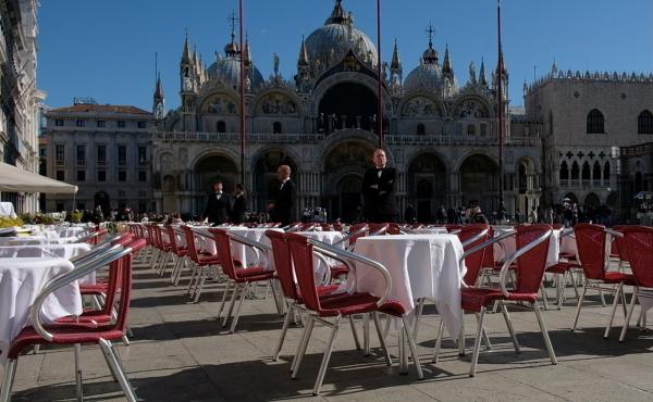 Waiters stand by an empty restaurant in Venice's St. Mark's Square, which would normally be full of tourists, as a coronavirus outbreak grows in Italy. Waiters stand by an empty restaurant in Venice's St. Mark's Square, which would normally be full of tourists, as a coronavirus outbreak grows in Italy.