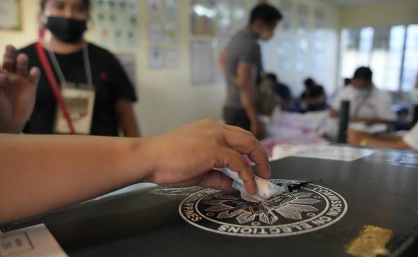 An election worker places a voting receipt inside a box at a polling center Monday in Quezon City, Philippines. An election worker places a voting receipt inside a box at a polling center Monday in Quezon City, Philippines.