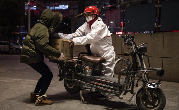 A delivery person wears a protective mask and suit as he delivers packages by bicycle on Saturday in Wuhan, China. A delivery person wears a protective mask and suit as he delivers packages by bicycle on Saturday in Wuhan, China.