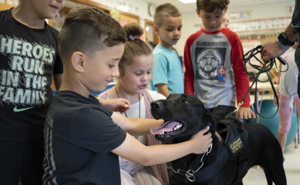 Freetown Elementary School students Mason Santos, left, and Mila Talbot, right, pet Huntah the dog after she finishes checking a classroom. Freetown Elementary School students Mason Santos, left, and Mila Talbot, right, pet Huntah the dog after she finishes checking a classroom.