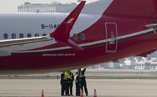 Members of the ground crew chat near a Boeing 737 Max 8 plane operated by Shanghai Airlines and parked on the tarmac at Shanghai Hongqiao International Airport in China. On Monday, the Civil Aviation Administration of China ordered all the country's airli Members of the ground crew chat near a Boeing 737 Max 8 plane operated by Shanghai Airlines and parked on the tarmac at Shanghai Hongqiao International Airport in China. On Monday, the Civil Aviation Administration of China ordered all the country's airli
