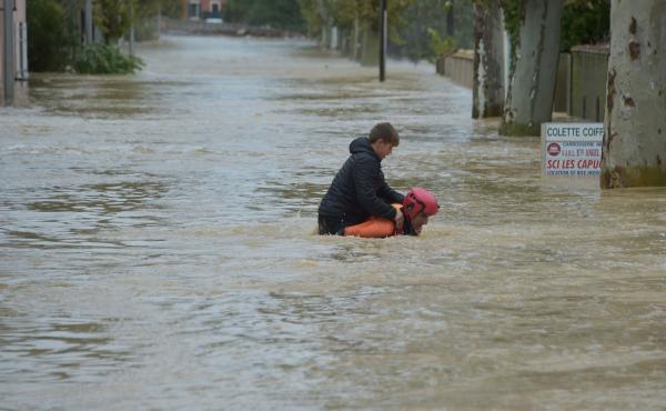A firefighter helps a youngster reach safety in a flooded street during a rescue operation following heavy rains that saw rivers bursting their banks in Trèbes, near Carcassonne, in southern France. A firefighter helps a youngster reach safety in a flooded street during a rescue operation following heavy rains that saw rivers bursting their banks in Trèbes, near Carcassonne, in southern France.