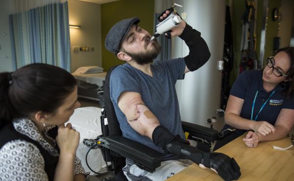 Fiancee Jessica Paker looks on as Ret. Marine Sgt. John Peck works with occupational therapist Meredith Grinnell. Peck, who was injured in Afghanistan in 2010, recently received a double arm transplant after a two-year wait on a transplant list. Fiancee Jessica Paker looks on as Ret. Marine Sgt. John Peck works with occupational therapist Meredith Grinnell. Peck, who was injured in Afghanistan in 2010, recently received a double arm transplant after a two-year wait on a transplant list.