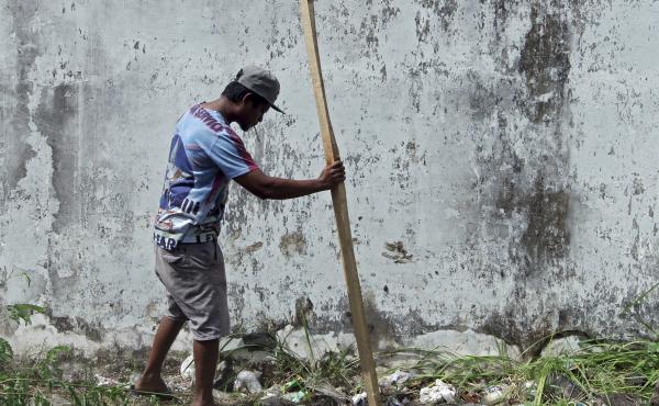 A man puts a wooden stick into a hole through which four foreign inmates escaped from Kerobokan prison in Bali Monday. A man puts a wooden stick into a hole through which four foreign inmates escaped from Kerobokan prison in Bali Monday.