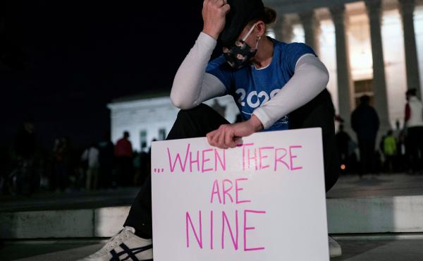 A woman, mourning the death of Ruth Bader Ginsburg, holds a sign at the Supreme Court that reads, "when there are nine," something Ginsburg said to describe when there'd be enough women on the court. A woman, mourning the death of Ruth Bader Ginsburg, holds a sign at the Supreme Court that reads, "when there are nine," something Ginsburg said to describe when there'd be enough women on the court.