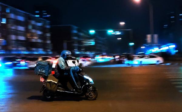 A courier delivers goods at night on a street in Beijing in February. A courier delivers goods at night on a street in Beijing in February.