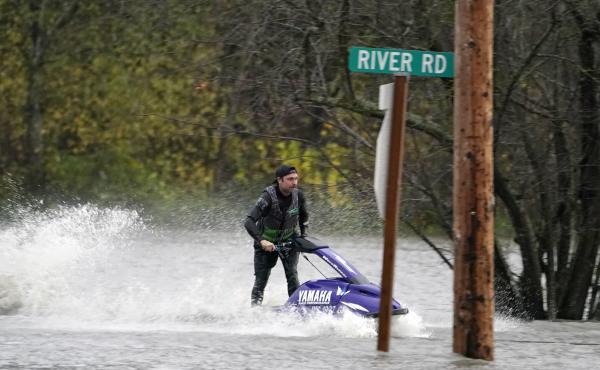 A man operates a personal watercraft along a road flooded by water from the Skagit River on Monday in Sedro-Woolley, Wash. A man operates a personal watercraft along a road flooded by water from the Skagit River on Monday in Sedro-Woolley, Wash.