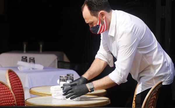 A restaurant server in New York prepares a table. But people remain cautious about going out and spending money. A restaurant server in New York prepares a table. But people remain cautious about going out and spending money.