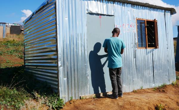 Ayanda stands in the doorway of a shack that he put up on illegally on privately owned farmland in Stellenbosch wine country. He says he grew tired of waiting for housing while living in Kayamandi township. Ayanda stands in the doorway of a shack that he put up on illegally on privately owned farmland in Stellenbosch wine country. He says he grew tired of waiting for housing while living in Kayamandi township.