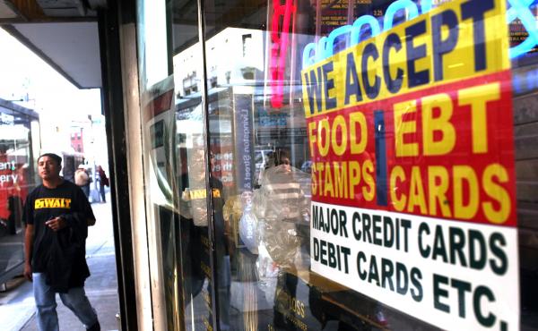 A sign in the window of a New York City market advertises the acceptance of food stamps. A sign in the window of a New York City market advertises the acceptance of food stamps.