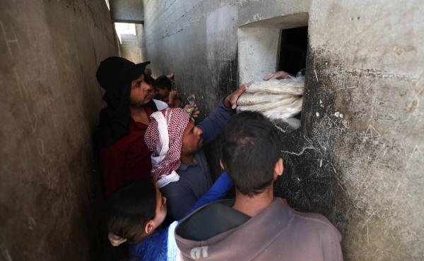 Syrians buy bread at a shop in the town of Binnish in the country's northwestern Idlib province in June. Nowadays, people say they're waiting up to six hours in line for a meager government bread ration. Syrians buy bread at a shop in the town of Binnish in the country's northwestern Idlib province in June. Nowadays, people say they're waiting up to six hours in line for a meager government bread ration.