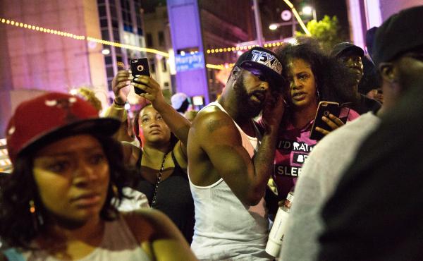 Protesters react as police officers arrest a bystander in downtown Dallas following Thursday's shooting. Protesters react as police officers arrest a bystander in downtown Dallas following Thursday's shooting.